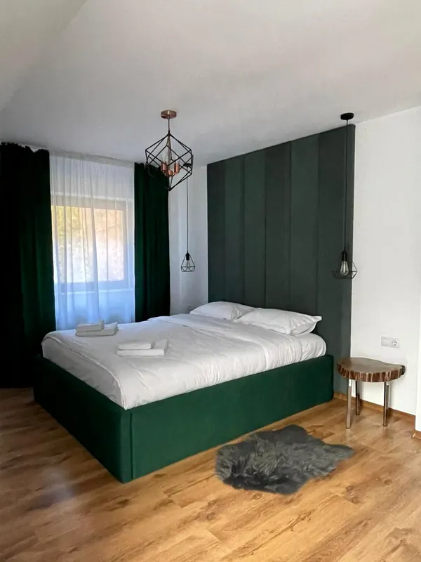 Dormitor cu pat verde și perete tapițat