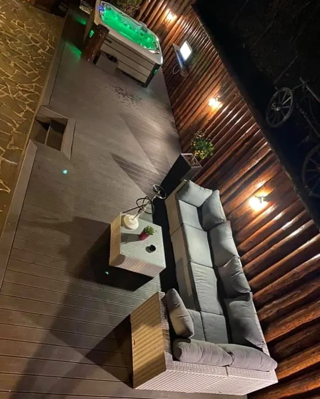 Terasa luminată seara, cu jacuzzi și canapele